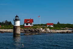 Red American Flag Waves  Between Red Roof Houses at Island Light